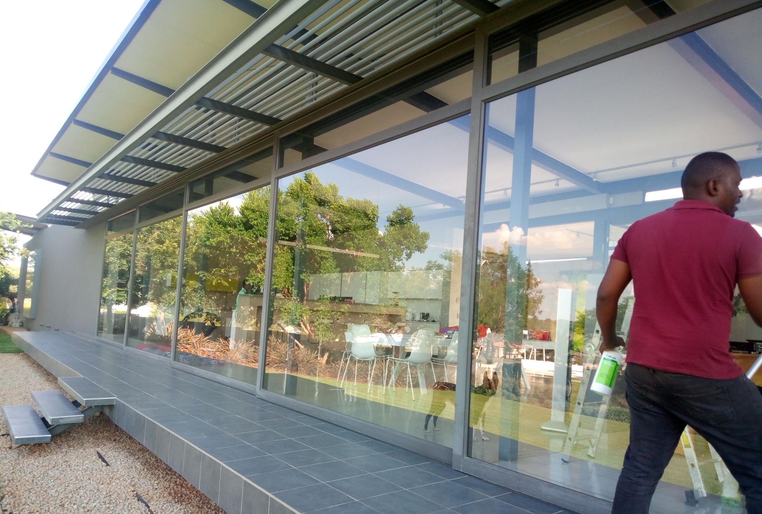Tall aluminium glazed frames along a covered patio, with an installer on site