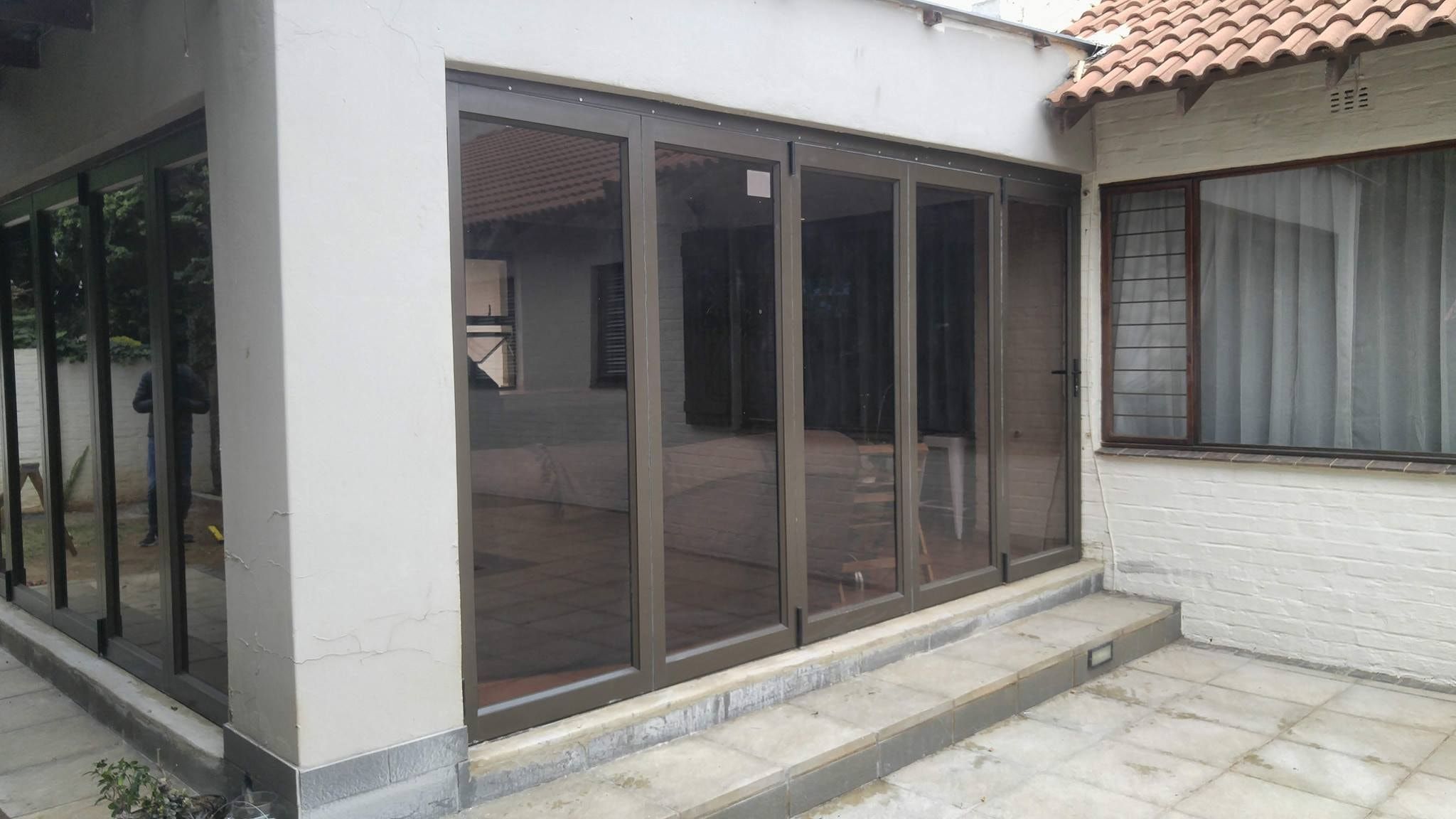 Bronze aluminium folding doors fitted along a paved patio
